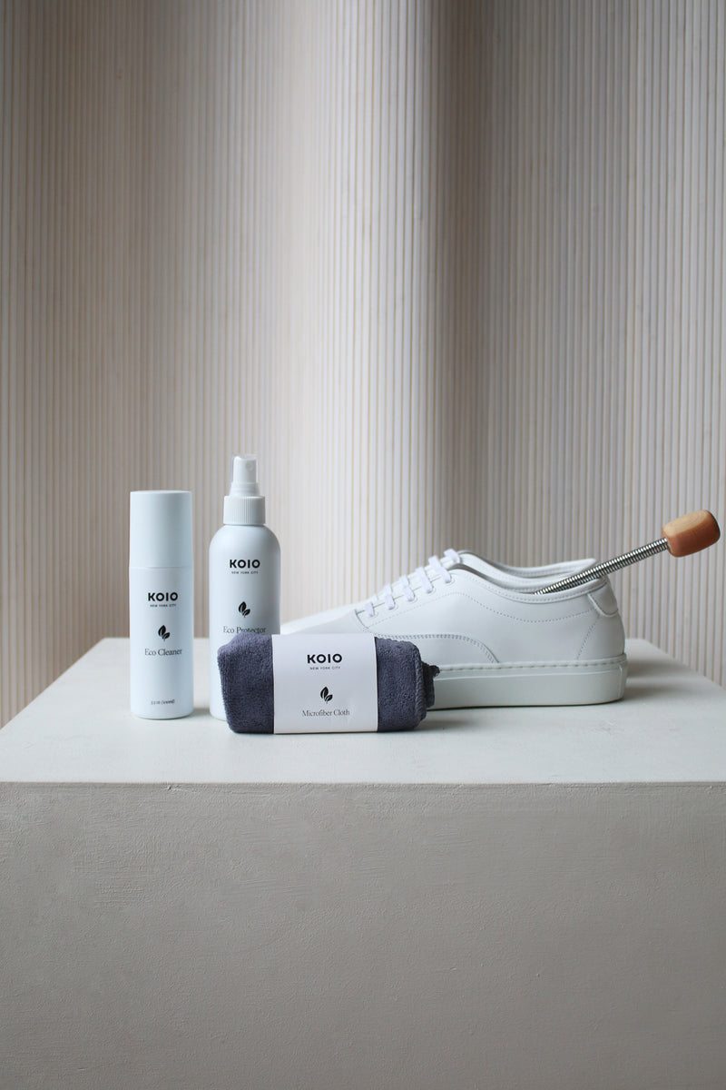 Italian white leather and canvas sneakers with laces on a table with shoe cleaning product accessories