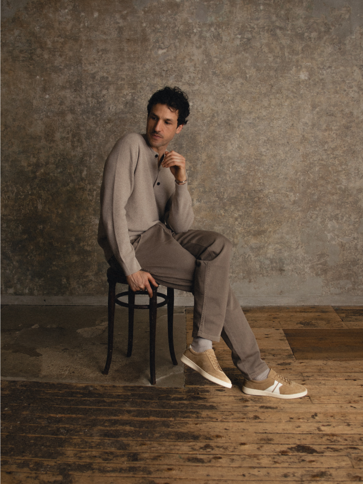 Man sitting on a chair wearing men's Italian light brown suede leather sneakers with laces and beige rubber soles